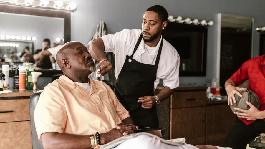 Un barbier travaille sur un client dans son salon