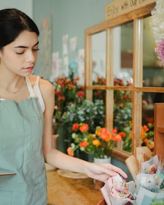 Une fleuriste prépare une composition dans sa boutique