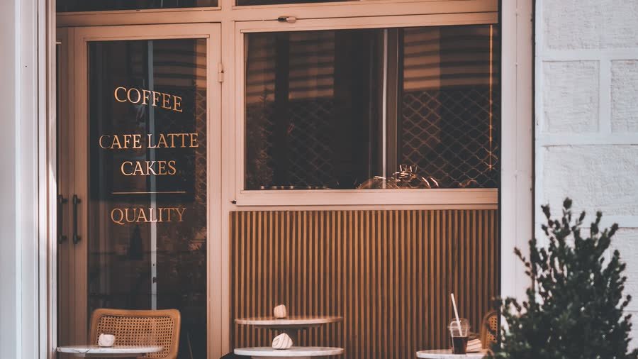 Vitrine d’un café avec son enseigne et ses horaires affichés