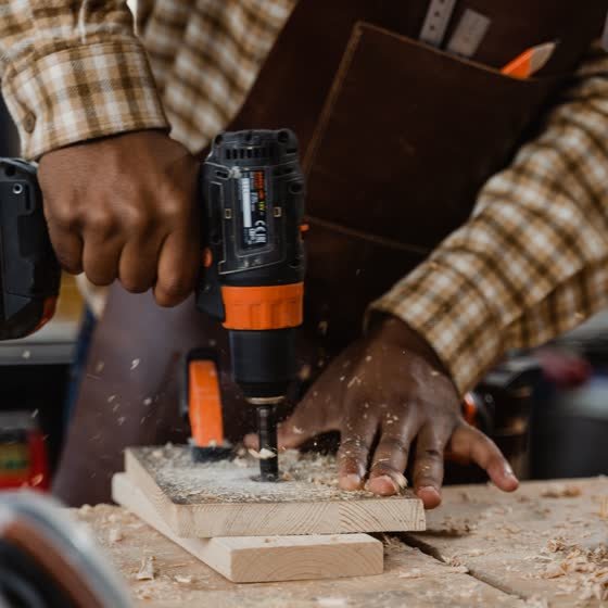 Gros plan sur des mains perçant une pièce de bois
